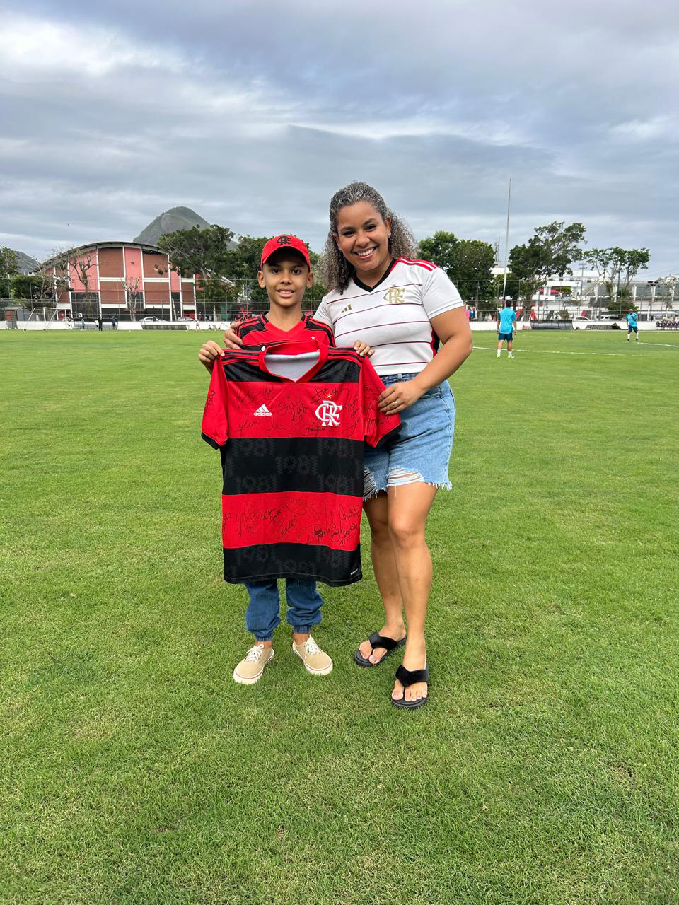 Davi, torcedor do Flamengo que se recupera de um câncer no cérebro, ao lado de sua mãe com uma camisa do Flamengo autografada pelo elenco do FlaMaster